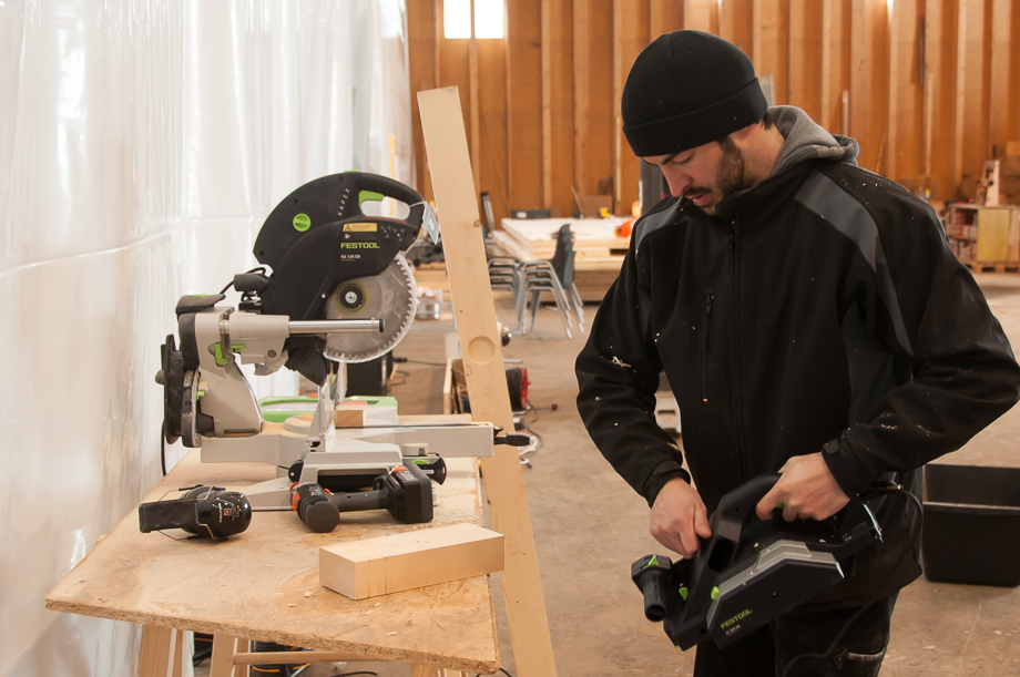 Johannes operating a rotary saw while wearing a hat