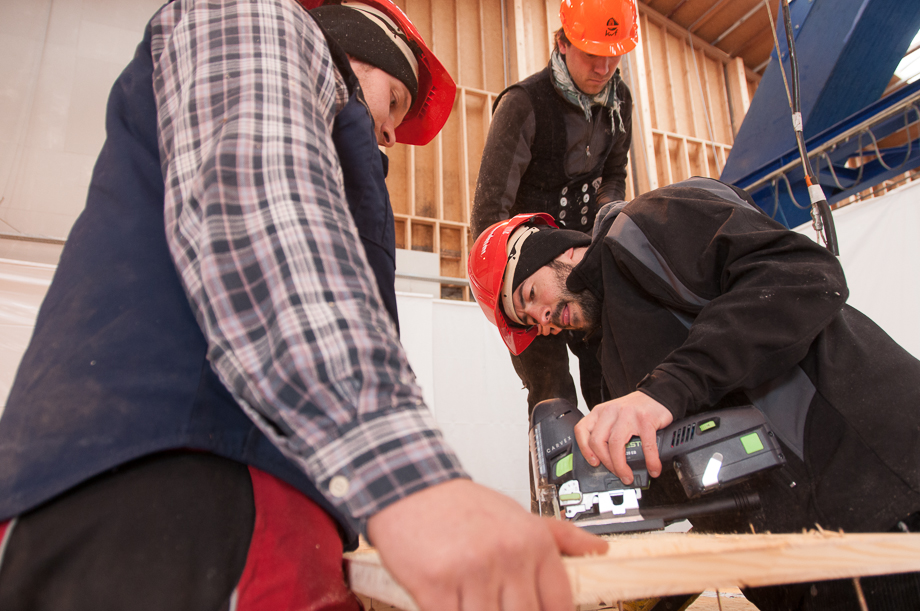 Two decathletes sawing a piece of wood two