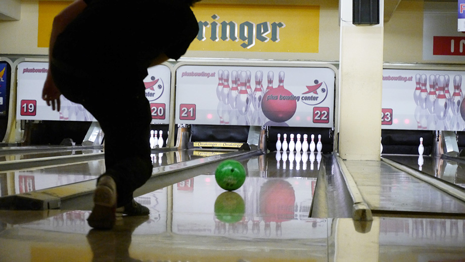 Faces of team members looking anxiously at the display over the bowling lane