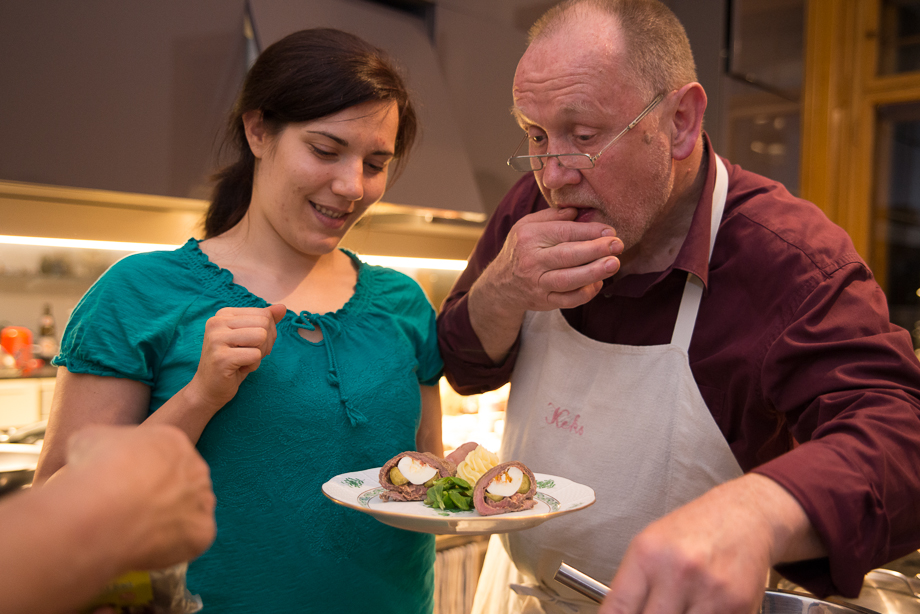 Daniela is smiling down at her plate while the chef is licking his fingers