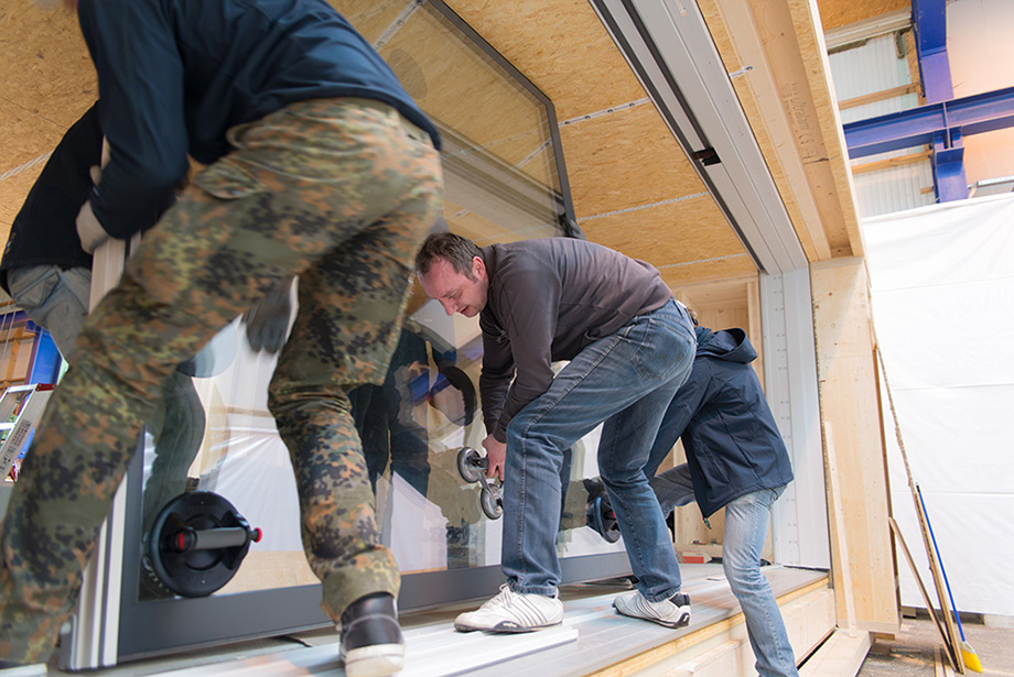 Six people slowly fitting the window into the frame