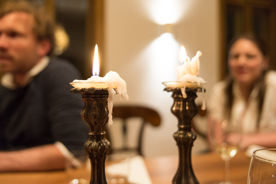 Macro of candles burning down. In the background are people talking.