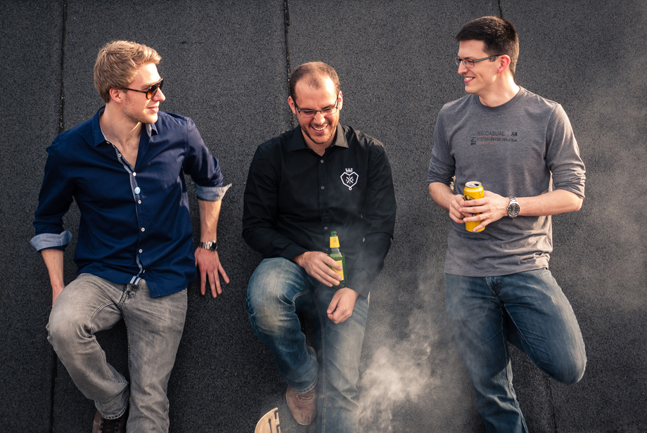 Three decathletes playing it cool by leaning against a wall