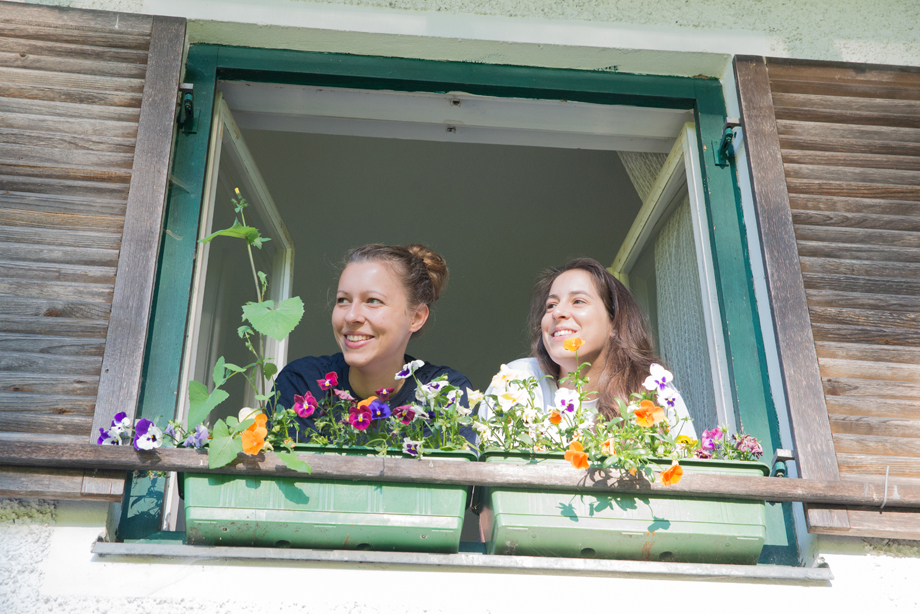 Two girls looking out a window of a rural house