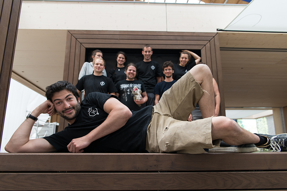 The team is posing in front of the finished house. Johannes is lying in the foreground.