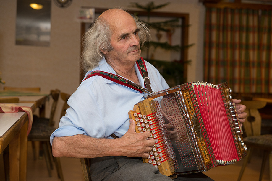 Same old man. He is playing the accordion.