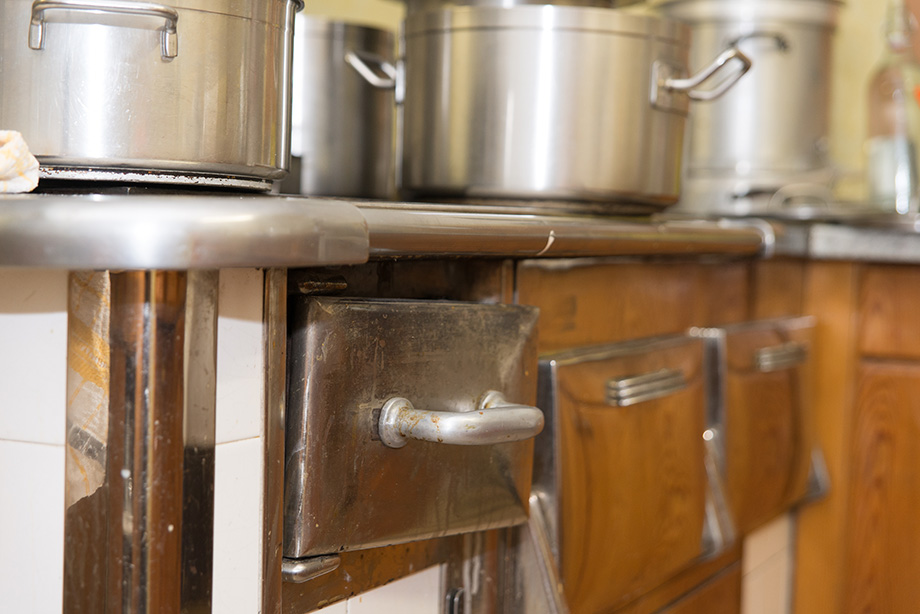 An old fashioned stove with metal drawers.