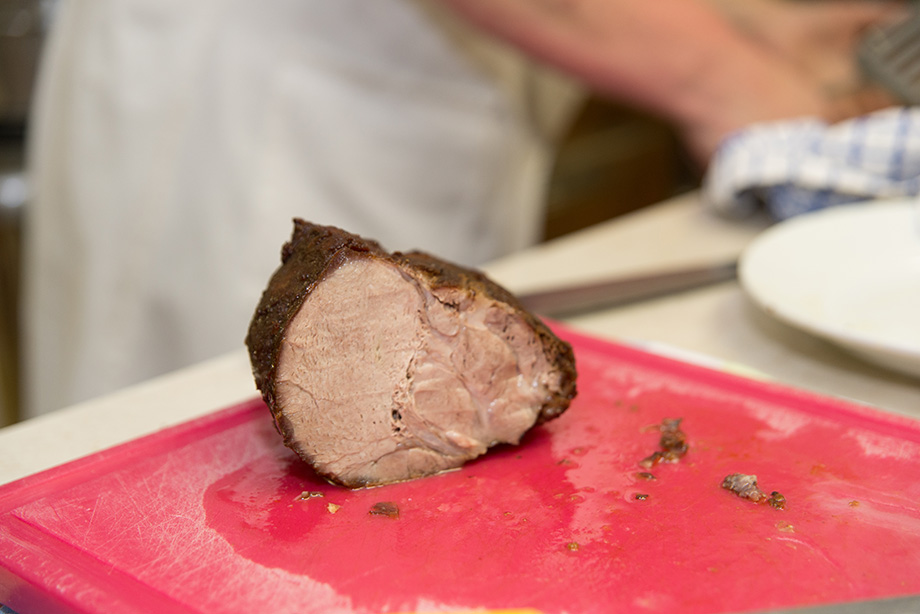 A sliced piece of meat on a red cutting board.