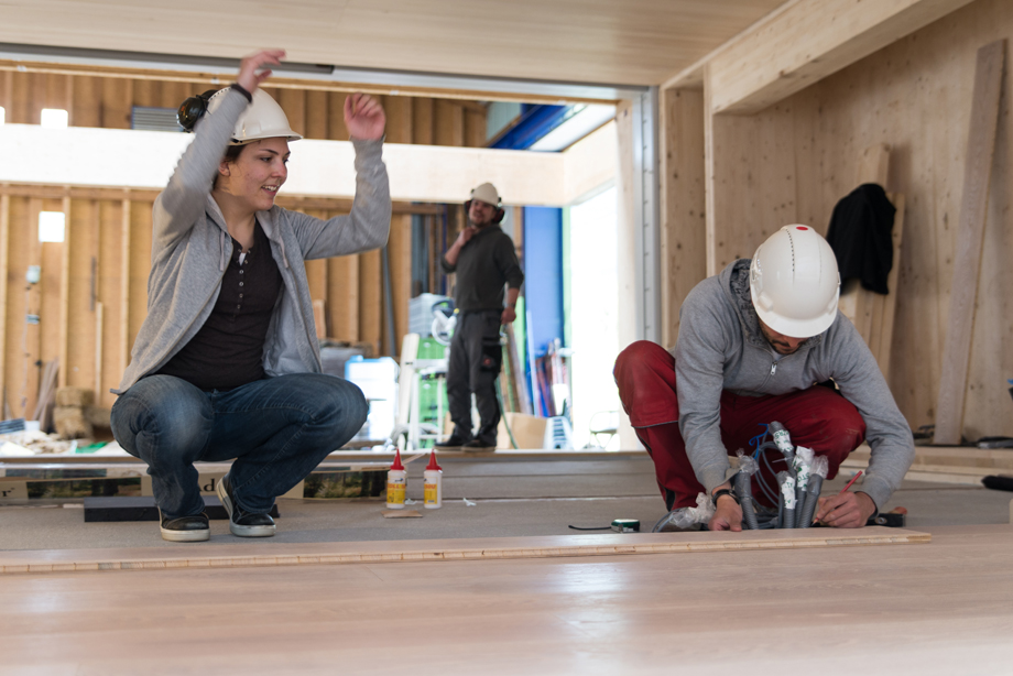 Two decathletes placing the parquet inside the living area.