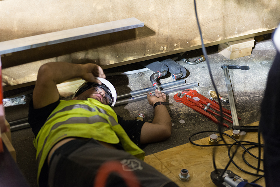 A decathlete lying on the floor installing something beneath the house.