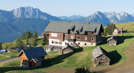 The house of the old man is situated on a mountain slope looking at a beautiful alpine landscape.
