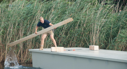 Decathlete Wolfgang is paddling on a pontoon. He is using a piece of wood.